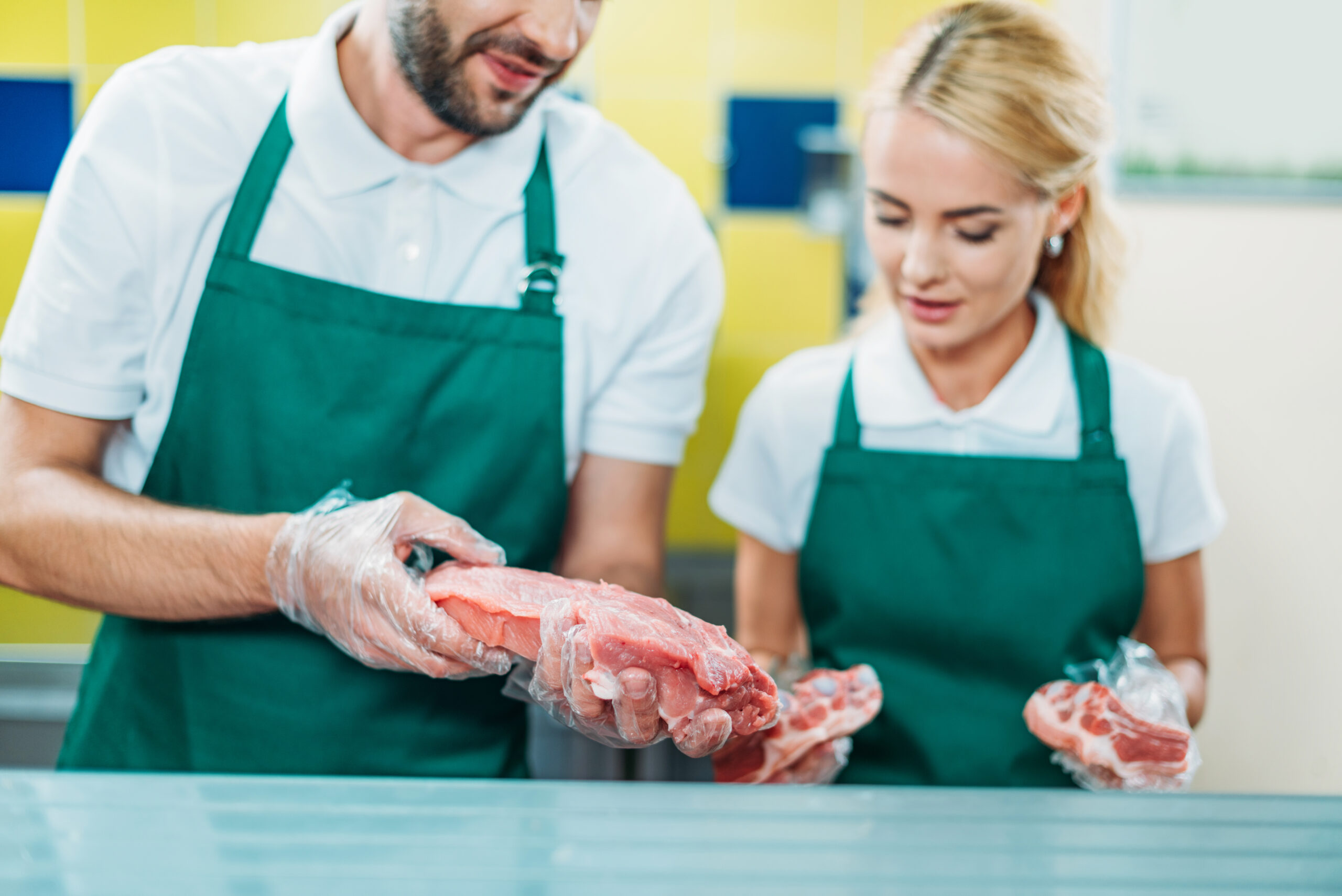 selective focus of shop assistants working with fresh raw meat in supermarket